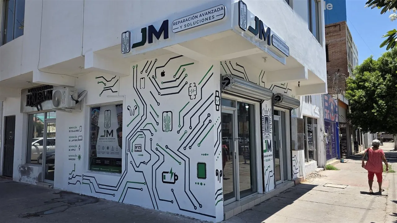 Fachada del local de JM Reparación Avanzada y Soluciones: muro blanco con pistas de circuito pintadas en azul y verde
